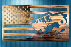 Metal wall art depicting a Jeep climbing a mountain inside an American Flag with a Wood Grain Copper Patina finish on the metal.
