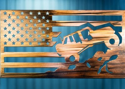 Metal wall art depicting a Jeep climbing a mountain inside an American Flag with a Wood Grain Copper Patina finish on the metal.
