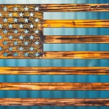 American Flag Metal Art wall decor depicting an American Flag cut out of metal. Picture shows a Wood Grain Copper Patina finish.