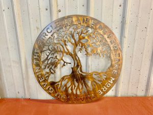 Circular metal wall art with a tree in the middle and the phrase In The Circle of Life Never Give More Than You Take
