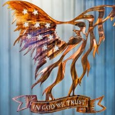 Metal wall art of American Bald Eagle with expanded wings depicting American Flag and holding In God We Trust banner in talons all cut out of metal with a Wood Grain Copper Patina.