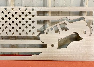 Metal wall art depicting a Jeep climbing a mountain inside an American Flag with a Clear Coat finish on the metal.
