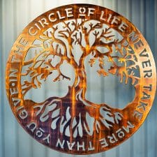 Circular metal wall art with a tree in the middle and the phrase In The Circle of Life Never Give More Than You Take