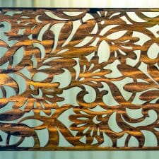 Metal wall art screen with floral pattern cut out of metal on wood grain copper patina finish