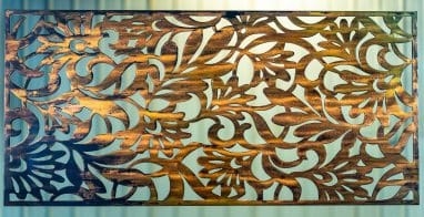 Metal wall art screen with floral pattern cut out of metal on wood grain copper patina finish