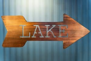Metal wall art of Lake directional sign - Right facing - with metal shaped arrow with Lake cut into the middle. This piece has a wood grain copper patina finish.