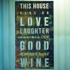 Metal wall art sign saying This House Runs on Love, Laughter and Really Good Bottles of Wine