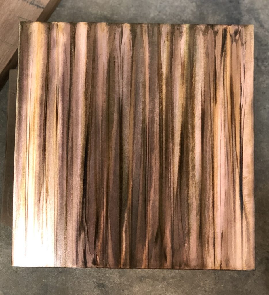 Sample photo of a wood grain copper patina finish from Artful MetalWorx metal art. The metal has a bright silver look that accents the polished steel showing the grinder marks where the metal was hand finished.